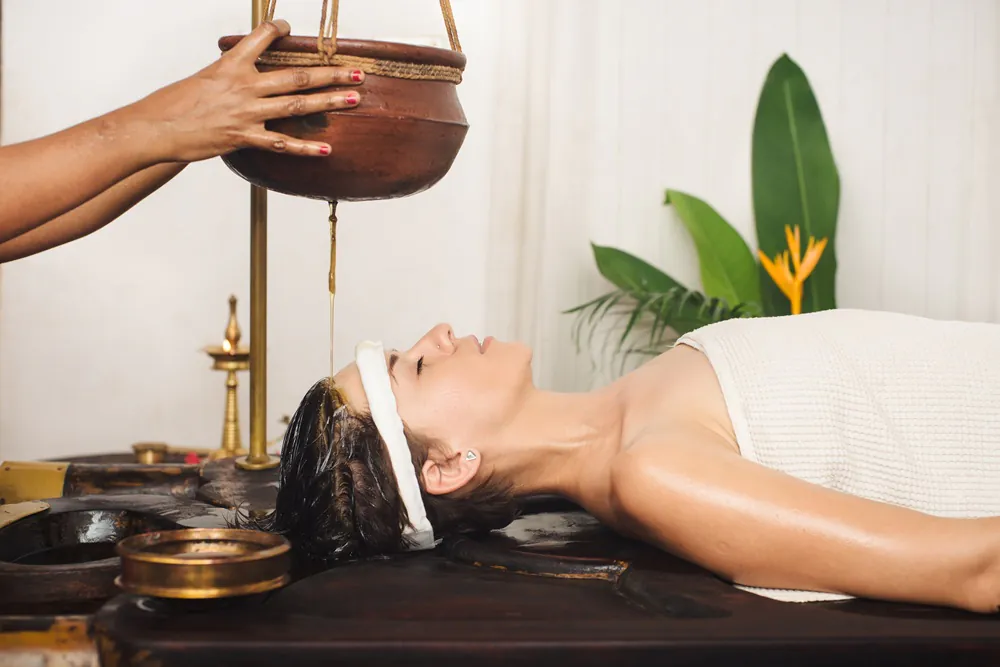 A guest receiving a Shirodhara treatment